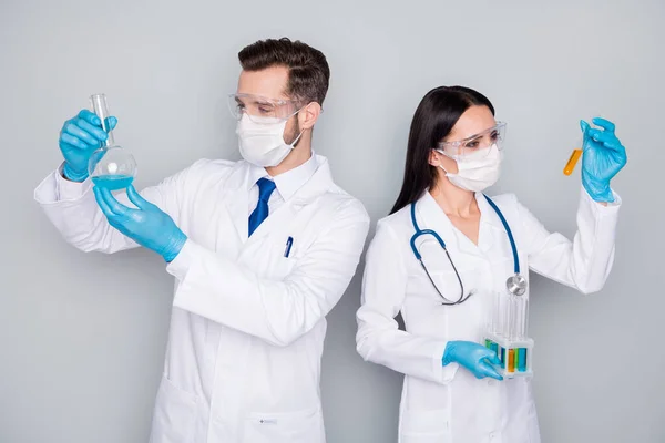 Photo of specialists doc guy lady virology clinic experienced doctors hold blood probe chemical experiment infection vaccine wear protect mask gloves lab coat isolated grey color background — Stock Photo, Image