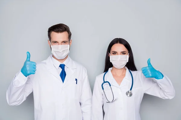 Foto van professionele ervaren doc guy dame virologie kliniek verhogen duimen omhoog eens infectie preventie controle dragen beschermende maskers latex handschoenen lab jassen geïsoleerde grijze kleur achtergrond — Stockfoto