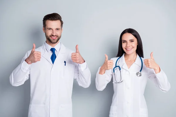 Foto de la señora guapo doc chico dos personas consulta de emergencia paciente virología clínica pulgares hacia arriba aprobar la condición de salud médicos experimentados usan batas de laboratorio aislado fondo de color gris — Foto de Stock