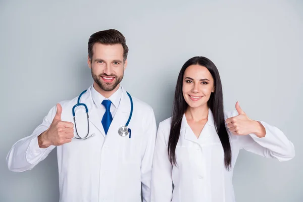 Photo of handsome doc guy lady two people emergency patient consultation virology clinic thumbs up approve health condition experienced doctors wear lab coats isolated grey color background — Stock Photo, Image