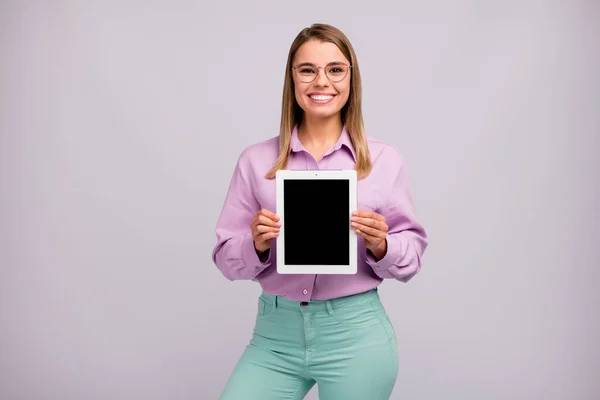 Porträtt av positiva glada flicka promotor hålla ny enhet nyhet tablett föreslå vissa annonser promo bära bra utseende kläder isolerade över grå färg bakgrund — Stockfoto