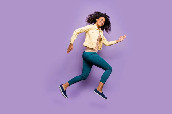 Longitud completa tamaño corporal foto de alegre positivo linda chica bonita en pantalones pantalones camisa amarillo corriendo saltar aislado pastel violeta color fondo —  Fotos de Stock