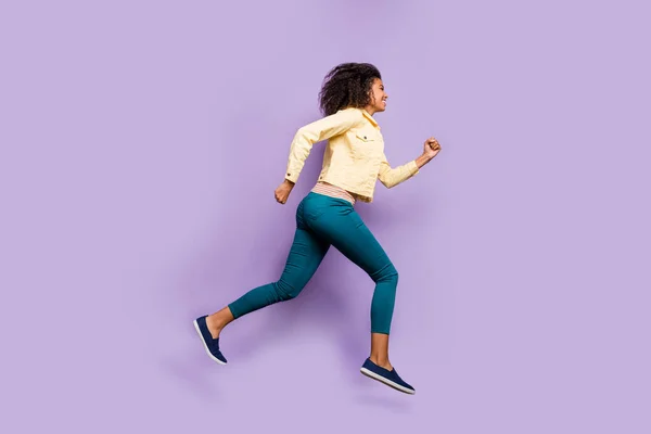 Πλευρικό προφίλ πλήρους μήκους του σώματος φωτογραφία του χαρούμενα θετικά χαριτωμένο όμορφο κορίτσι τρέχει στο εμπορικό κέντρο σε παντελόνι παπούτσια παντελόνι απομονωμένο παστέλ βιολετί χρώμα φόντο — Φωτογραφία Αρχείου