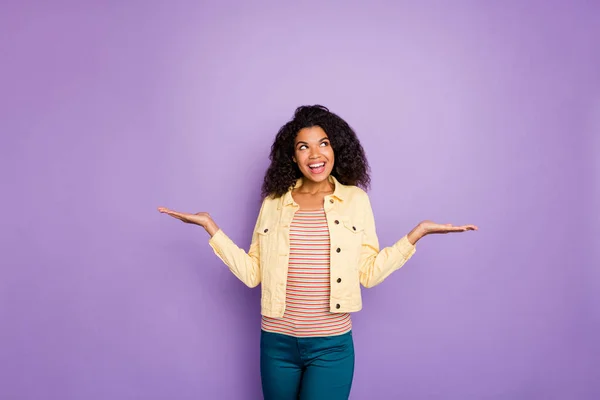 Retrato de la chica afro americana de mente interesada soñadora sostener la mano pesando objeto pensar pensamientos elección decisión solución usar estilo casual chaqueta amarilla aislado color violeta fondo — Foto de Stock