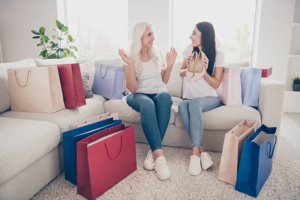 Foto de cuerpo entero dos personas pensionista mamá jubilada dar deseo zapatos de tacón alto hija que compra centro comercial consumismo chica disfrutar de 8-marzo sentarse acogedor sofá en casa en el interior —  Fotos de Stock