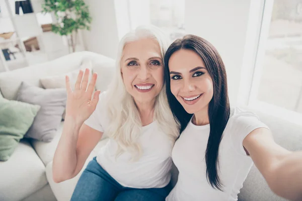 Close up photo of positive old woman mom her daughter make selfie have video call relatives abroad senior person sit comfort wave hand say hello in house indoors — Stock fotografie