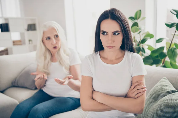 Close-up portrait of two nice attractive depressed women sitting on divan grandma talking claiming problems pretense disagree negative emotion in white light interior house flat apartment indoors — Stock Photo, Image