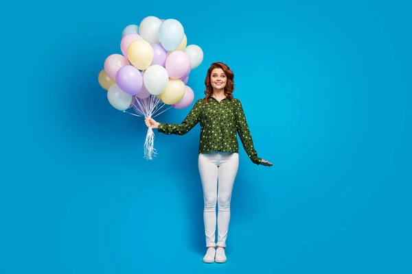 Ganzes Foto von hübschen schönen Dame halten viele bunte Luftballons besuchen besten Freund Geburtstagsparty tragen gepunktetes grünes Hemd weiße Hose Schuhe isoliert blaue Farbe Hintergrund — Stockfoto