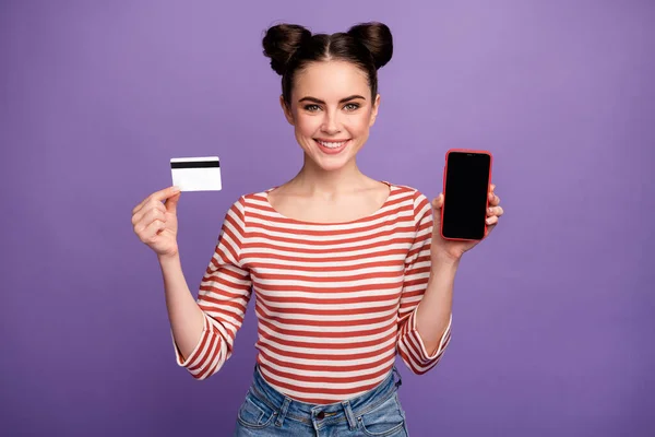Photo of cheerful lady hold credit card new model smart phone showing presenting service online payment wear white red casual striped shirt isolated purple pastel color background — Stock Photo, Image
