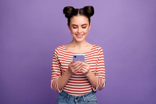 Photo of pretty lady two funny buns hold telephone hands toothy smiling check followers blog wear white red casual striped shirt isolated purple pastel color background