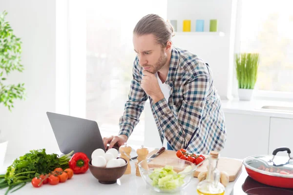 요리 잘 하네. 사려깊고 생각깊은 남자 라면맛있는 아침 식사를 준비하고 싶어 한다.아 내는 인터넷 요리 작업장을 찾고 있다. — 스톡 사진