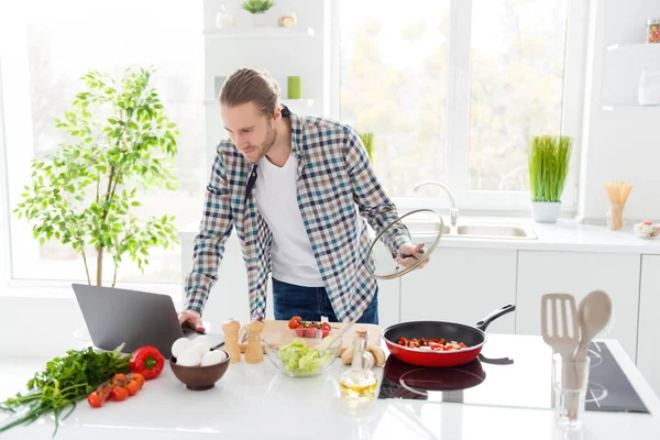 Retrato de cara focado quer cozinhar saborosa deliciosa manhã café da manhã olhar laptop verificar receita fritar refeição vegetariana desgaste casual xadrez camisa xadrez na casa da cozinha dentro de casa — Fotografia de Stock