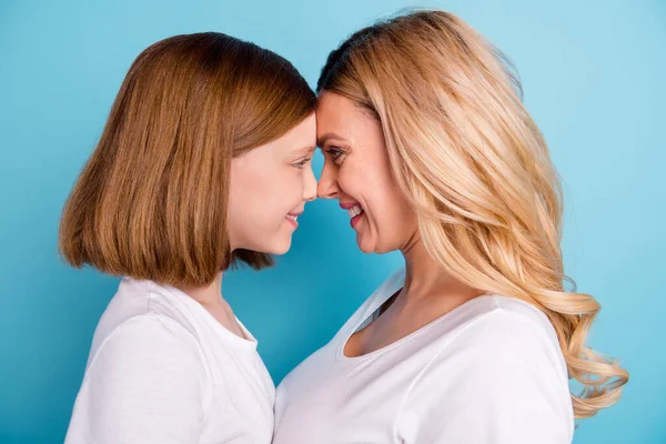 Primeros planos foto de perfil de dos personas hermosa mamá señora pequeña hija rubia mirada ojos inclinados cabeza a cabeza desgaste casual blanco s-camisas aislado color azul fondo — Foto de Stock