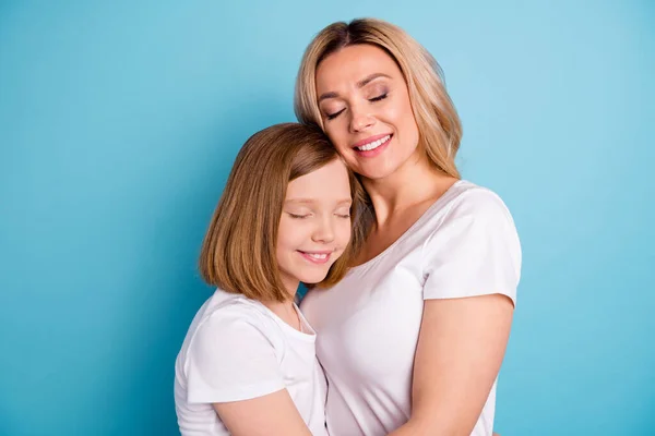 Profilfoto von zwei Personen schöne Mama Dame kleine Tochter Blonds Umarmung schiefen Kopf Augen geschlossen besten Freunde tragen lässige weiße T-Shirts isoliert blauen Farbhintergrund — Stockfoto