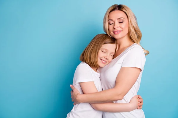 Φωτογραφία προφίλ δύο ανθρώπων νεαρή όμορφη μαμά κυρία μικρή κόρη αγκαλιάζει τα μάτια κλειστά κρατώντας τα χέρια στοργική φορούν casual λευκό s-shirts απομονωμένο φόντο μπλε χρώμα — Φωτογραφία Αρχείου