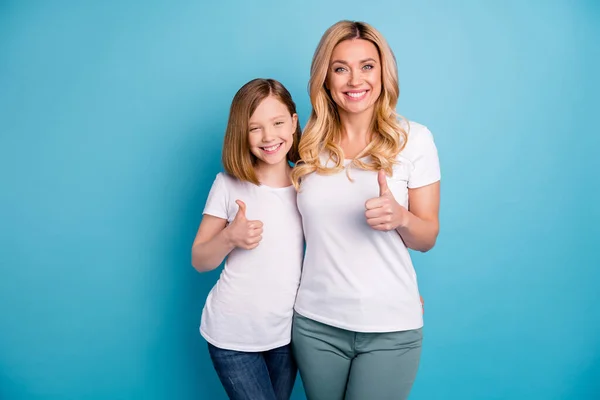 Foto av två personer attraktiv mamma dam lilla dotter hålla tummen fingrar upp uttrycklig överenskommelse glad person bära casual vita s-shirts isolerad blå färg bakgrund — Stockfoto
