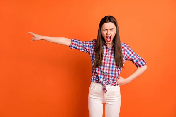 Foto van aantrekkelijke gekke dame directe vinger kant tonen cheat vriendje manier om te gaan schreeuwen boos dragen casual geruite shirt witte broek geïsoleerde helder oranje kleur achtergrond — Stockfoto