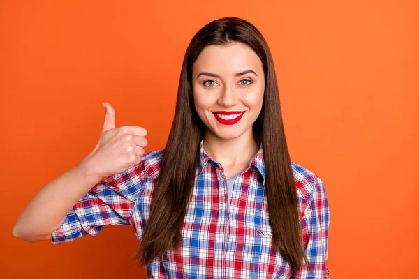 Foto de senhora atraente brilhante vermelho pomade toothy sorriso levantar dedo polegar até aprovar boa qualidade do produto desgaste casual xadrez camisa isolada vibrante cor laranja fundo — Fotografia de Stock