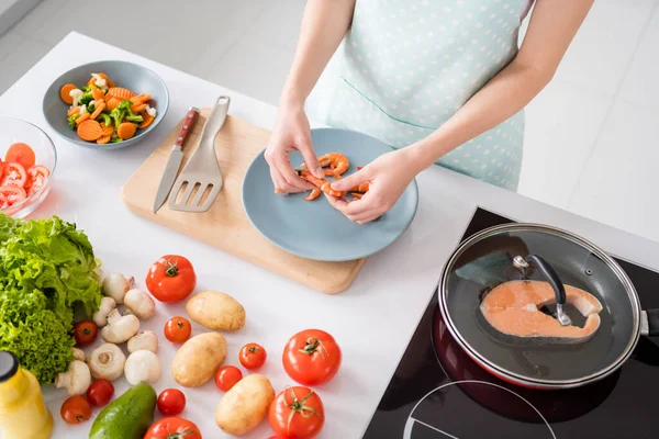 Vista de ángulo alto foto recortada de ama de casa señora escritorio pelar camarones hervidos cocina familia cena ingredientes preparados usar delantal camiseta pie cocina moderna en el interior — Foto de Stock