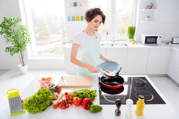 Foto van mooie huisvrouw dame zetten verse rauwe zalm filet biefstuk op vliegende pan houden dieet ochtend koken dragen schort t-shirt staan moderne gebruiksvoorwerpen keuken binnen — Stockfoto