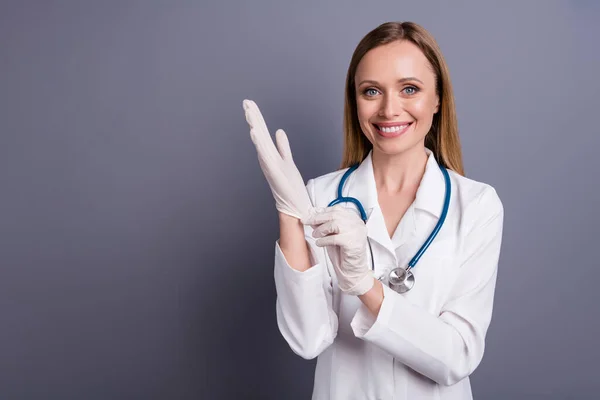 Close-up portret van mooie aantrekkelijke blonde meisje ervaren doc specialist chirurg zetten rubber handschoenen op het bereiden van chirurgie geïsoleerd over grijs violet pastel kleur achtergrond — Stockfoto