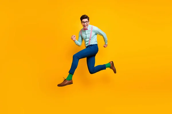 Full body profile photo of cool stylish guy jumping high up radostně spěchající nákupní centrum nosit specifikace košile motýlek šle kalhoty boty zelené ponožky izolované žlutá barva pozadí — Stock fotografie