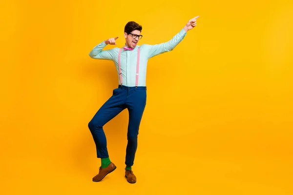 Foto de comprimento total de cara elegante legal namorado dançando humor festivo animado direto dedo lado desgaste especificações camisa arco gravata suspensórios calças sapatos isolados vívido cor amarela fundo — Fotografia de Stock