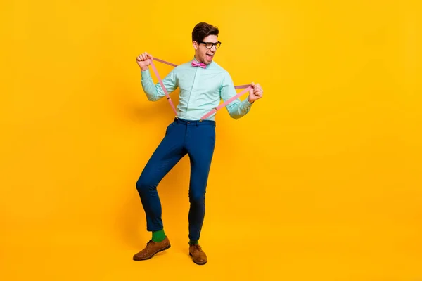 Full length photo of cool stylish guy boyfriend hands hold stretch suspenders festive mood scream excited wear specs shirt bow tie trousers shoes isolated vivid yellow color background — Stock Photo, Image