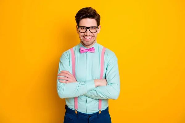 Foto van knappe coole kleding business guy staan zelfverzekerd handen gekruist stralende glimlach dragen specs shirt bretels strik broek geïsoleerde gele kleur achtergrond — Stockfoto
