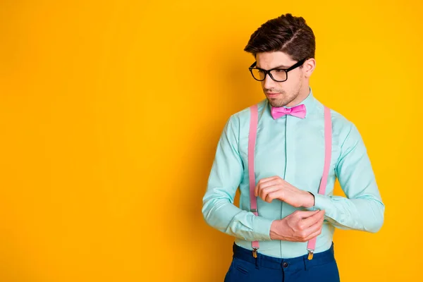 Foto van knappe coole kleren jonge man vriendje kijken lege ruimte serieus knopen shirt mouw slijtage specs teal shirt roze bretels strik geïsoleerde gele kleur achtergrond — Stockfoto