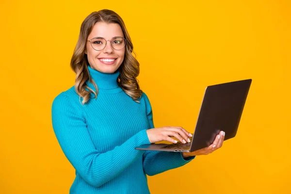 Foto de atractiva dama de negocios ondulado celebrar portátil de tecnología moderna lectura informe corporativo de correo electrónico en línea desgaste especificaciones azul cuello alto aislado de color amarillo brillante fondo — Foto de Stock