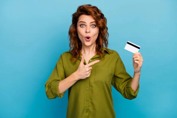 Подивіться на це неймовірно. Здивована жінка тримає точку індексу пальця кредитної картки, вражена легкою платною банківською послугою, носить стильний одяг, ізольований на фоні синього кольору — стокове фото