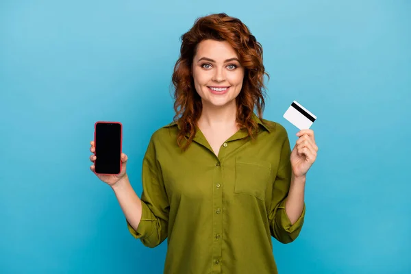 Портрет позитивної веселої жінки, що тримає кредитну картку смартфона, рекомендуємо оплатити покупку онлайн-сервісу банківського обслуговування, гарний вигляд стильний одяг ізольований на фоні синього кольору — стокове фото
