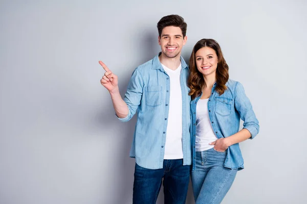 Retrato de pareja alegre positiva dedo índice dedo dedo presente publicidad promoción desgaste ropa de estilo casual aislado sobre fondo de color gris —  Fotos de Stock