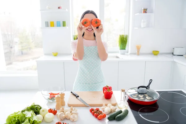 Retrato dela ela agradável atraente agradável alegre alegre alegre menina brincalhão fazendo refeição divertida tomate como binóculos na moderna cozinha de estilo interior de luz branca dentro de casa — Fotografia de Stock