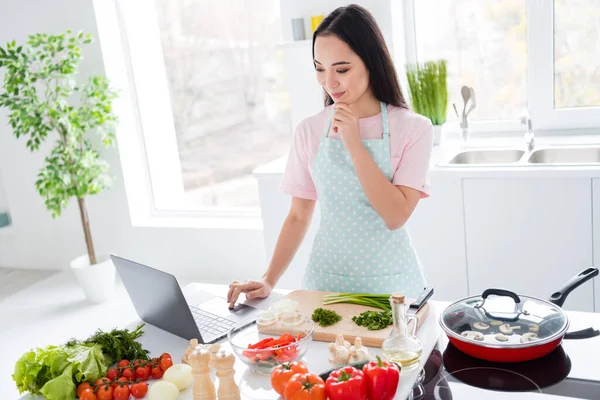 Фото красивої азіатської домогосподарки, яка ріже свіжі овочі, змішуючи салатні інгредієнти, готуючи смачну веганську страву, дивіться пошук в онлайн-блогері ноутбук стоїть на кухні в приміщенні — стокове фото