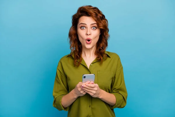 Портрет дивовижної божевільної жінки використовує смартфон, вражений соціальною мережею неймовірною інформацією, одягнений у гарний наряд, ізольований на фоні синього кольору — стокове фото