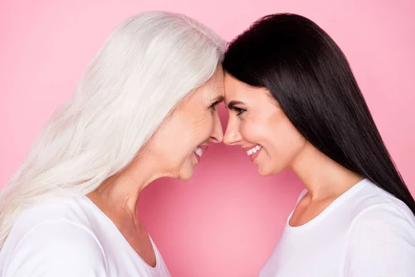 Primeros planos foto de perfil de la madre bastante anciana joven hija damas de pie frente opuesta magra mirada cariñosa ojos desgaste casual blanco camisetas aisladas pastel rosa color fondo — Foto de Stock