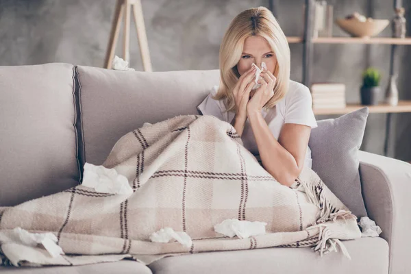 Portrait of her she nice attractive sick mature lady sitting on divan feeling bad blowing nose sneezing sick leave in modern industrial loft interior style living-room apartment — Stock Photo, Image