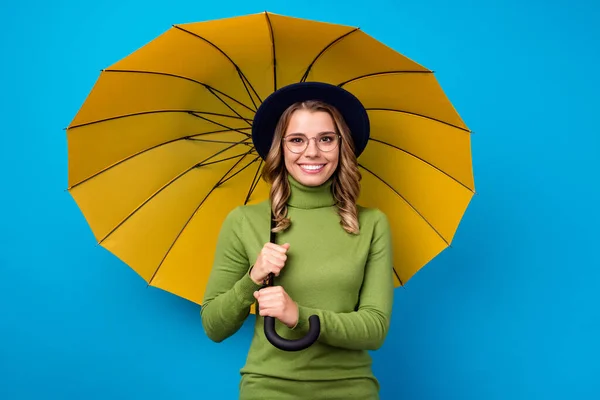 Foto de alegre señora rizada divertida gran paraguas caminar calle lluvioso cálido primavera buen humor después de larga cuarentena desgaste especificaciones sombrero verde cuello alto aislado color azul fondo — Foto de Stock