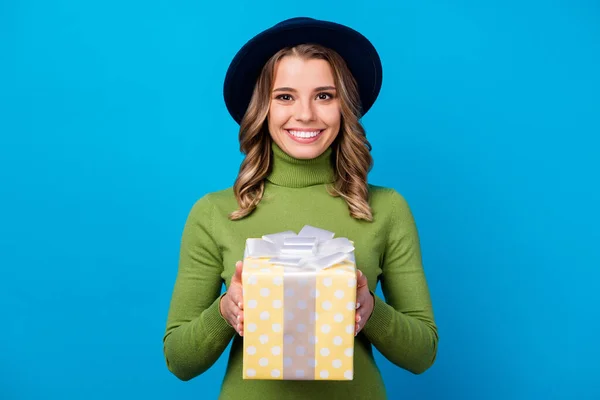 Fotografie atraktivní veselá dáma držet velké žluté tečkované dárek box narozeniny dárek strana host nosit retro klobouk ležérní zelená rolák izolované modré barvy pozadí — Stock fotografie