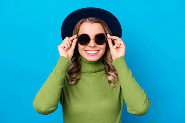 Foto de alegre engraçado ondulado senhora radiante sorrindo colocando sol especificações roupas para ao ar livre andar chapéu casual verde gola alta isolado azul cor fundo — Fotografia de Stock