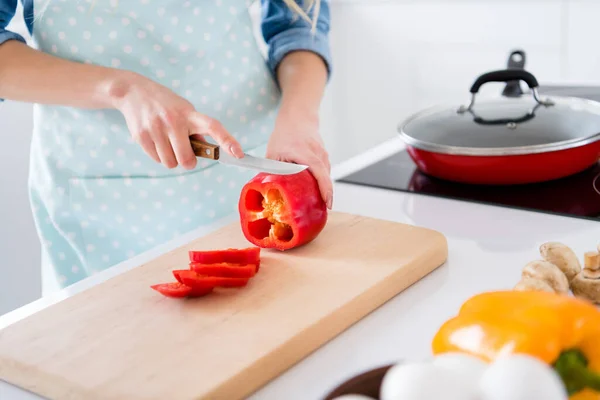 Gesneden profiel foto van huisvrouw chef-kok armen met grote rode peper bel snijden mes plakken genieten 's morgens koken smakelijk diner familie vergadering dragen schort shirt staan moderne keuken binnen — Stockfoto