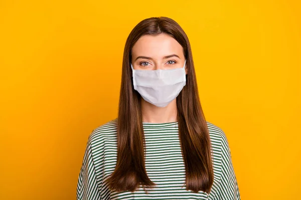 Foto van meisje staan in de voorkant van de camera en proberen niet te knipperen houden sociale afstand dragen medisch masker geïsoleerd met gele achtergrond — Stockfoto