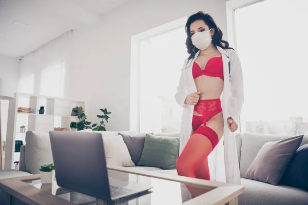 Photo of tender hot lady work home online chat service talk client undressing his wish play seduce nurse role take off lab coat look notebook screen wear red bikini flu mask room indoors