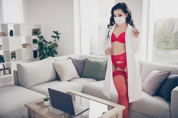 Private party. Photo of tender hot lady escort work home online service talk client undressing play nurse intern role take off lab white coat look notebook wear red bikini flu mask room indoors