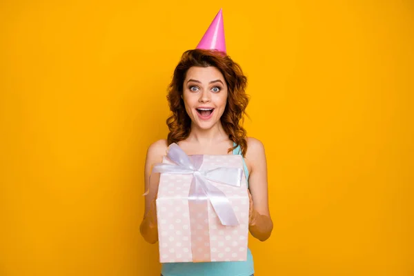 Foto van vrij grappige dame houden grote giftbox handen onverwachte geheim bewonderaar aanwezig dragen roze papier verjaardag cap casual teal tank-top geïsoleerde helder gele kleur achtergrond — Stockfoto