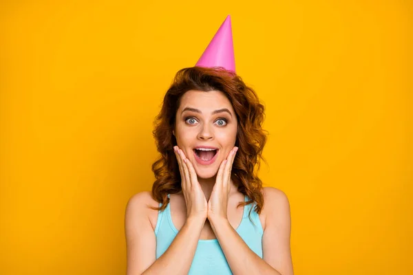 Close-up foto van vrij geschokte dame open mond armen op wangen onverwachte verrassing partij dragen papier verjaardag cap casual turquoise tank-top geïsoleerde heldere gele kleur achtergrond — Stockfoto