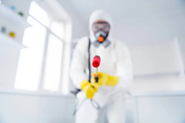 Blurred low angle view photo of sprayer cleaner hold latex gloves goggles coverall spray sanitize surface stop spreading ncov epidemic in house indoors