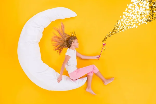 Top view above high angle flat lay flatlay lie concept view of blonde little small dreamy girl siting on white moon using magic stick charm isolated bright vivid shine vibrant yellow color background